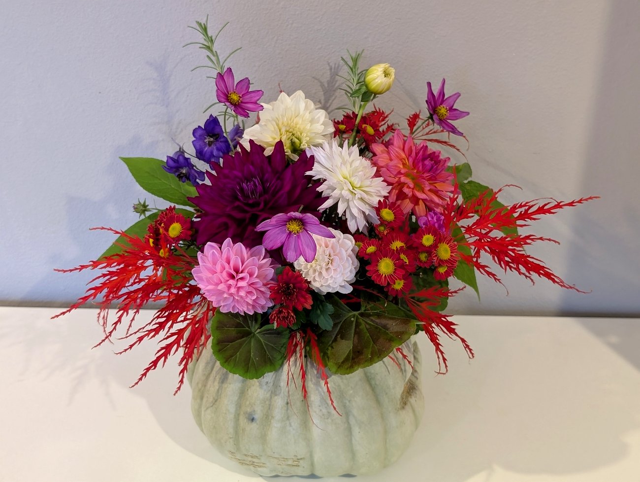 Autumn arrangement in an heirloom pumpkin — dahlias, chrysanthemums, and garden greens